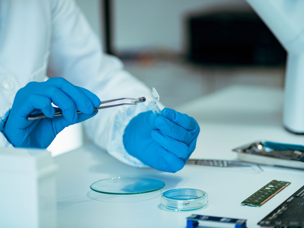 Gloved hands handling a small component in a lab